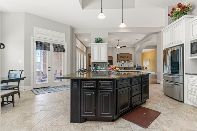 kitchen with white cabinetry, ceiling fan, hanging light fixtures, stainless steel fridge, and decorative backsplash