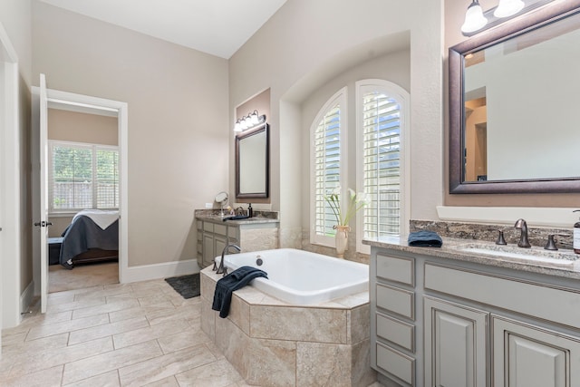 bathroom with vanity, a relaxing tiled tub, and plenty of natural light