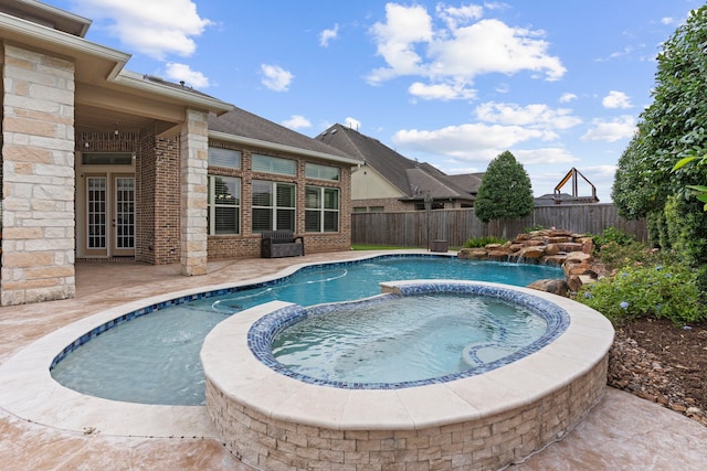 view of pool with an in ground hot tub, pool water feature, and a patio area