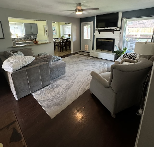 living room with ceiling fan, a fireplace, and wood-type flooring