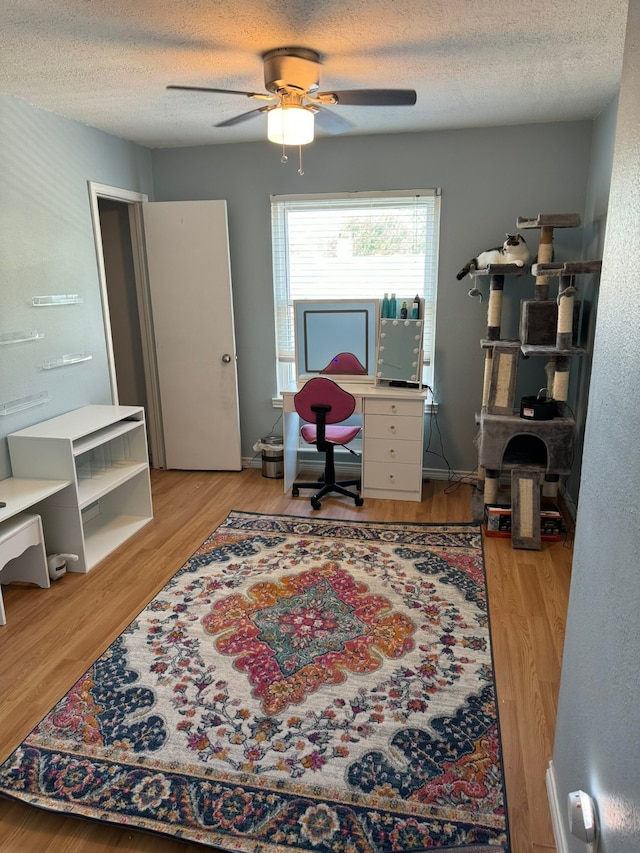 office area with ceiling fan, light wood-type flooring, and a textured ceiling