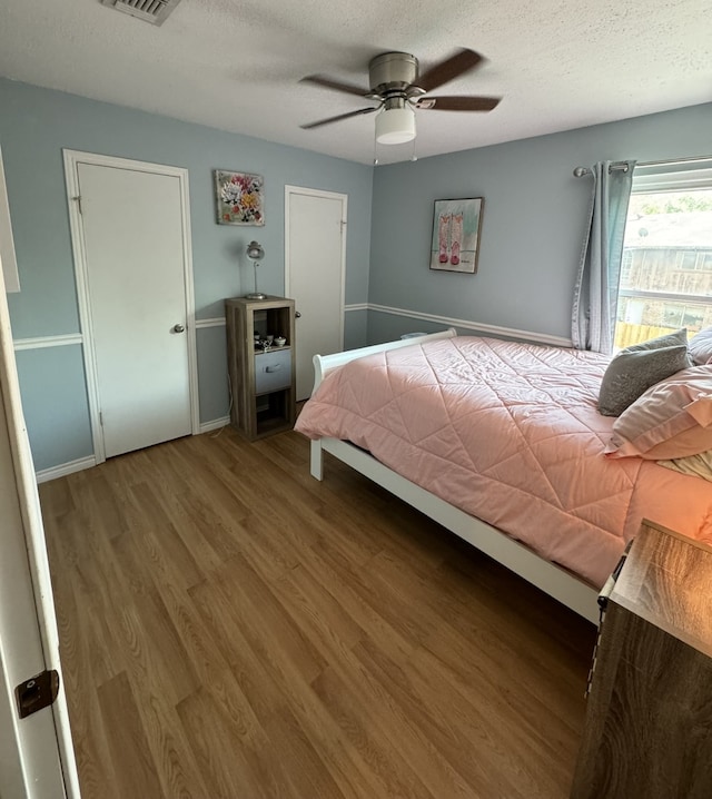 bedroom featuring ceiling fan, wood-type flooring, and a textured ceiling