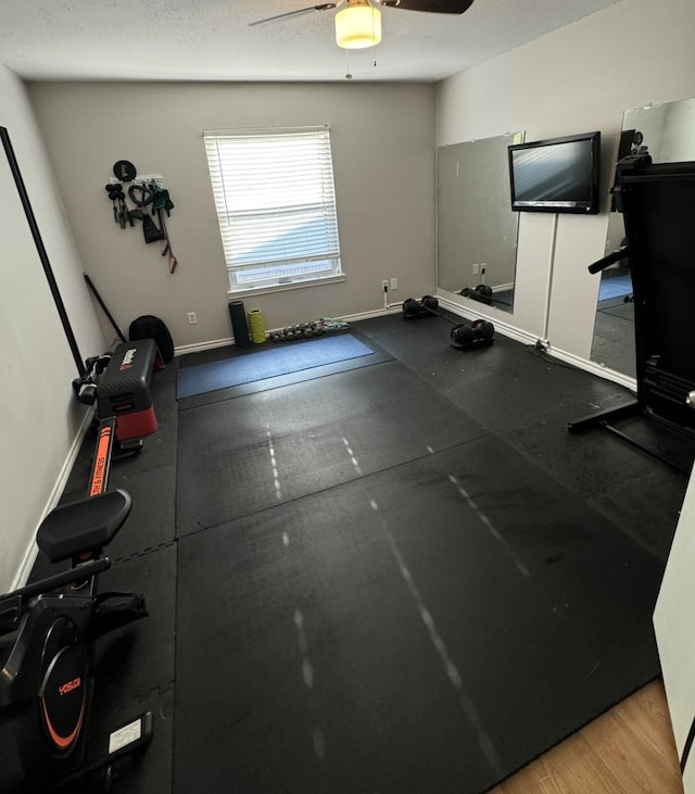 workout area featuring a textured ceiling, light wood-type flooring, and ceiling fan