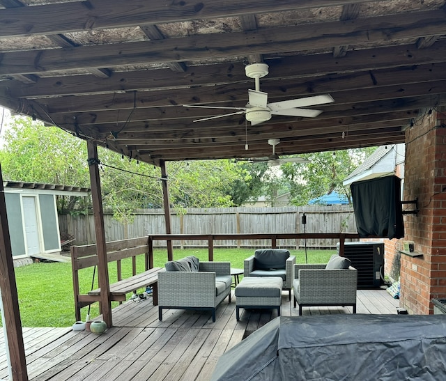 wooden deck with outdoor lounge area, a storage unit, ceiling fan, cooling unit, and a lawn