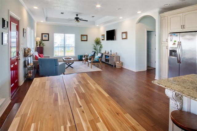 living room featuring ceiling fan, ornamental molding, hardwood / wood-style flooring, and a raised ceiling