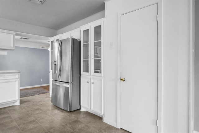 kitchen with stainless steel fridge, white cabinets, light tile patterned floors, and ceiling fan