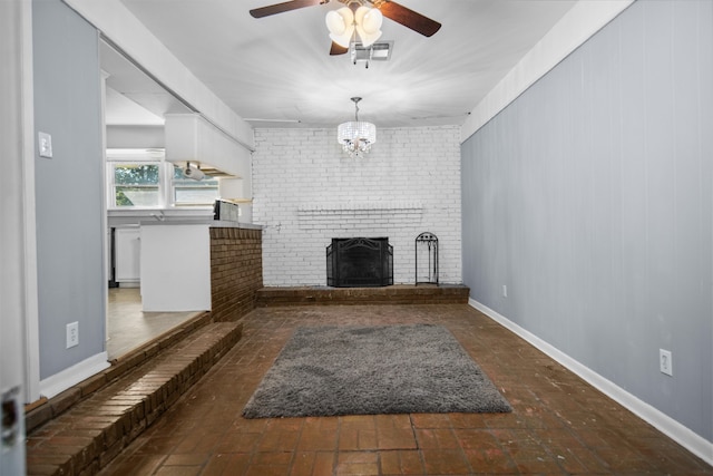 unfurnished living room with a fireplace, ceiling fan with notable chandelier, and brick wall