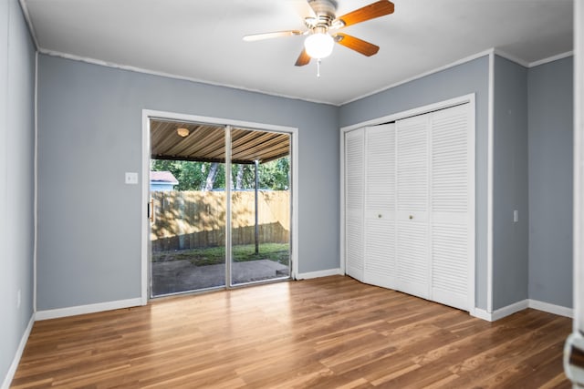 unfurnished bedroom featuring crown molding, hardwood / wood-style floors, access to outside, ceiling fan, and a closet