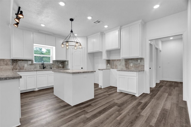 kitchen featuring dark hardwood / wood-style floors, white cabinetry, hanging light fixtures, a center island, and sink