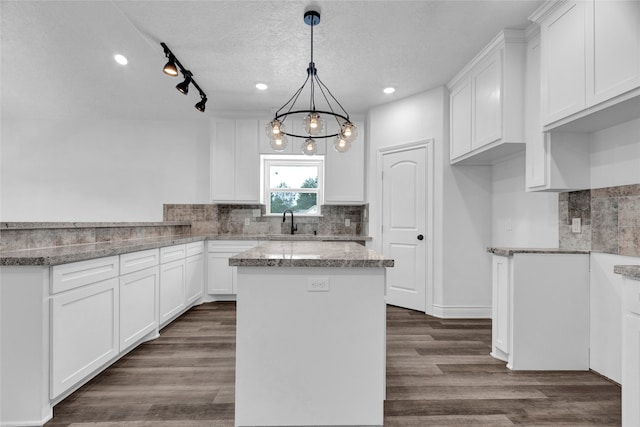 kitchen with dark wood-type flooring, pendant lighting, a textured ceiling, and rail lighting