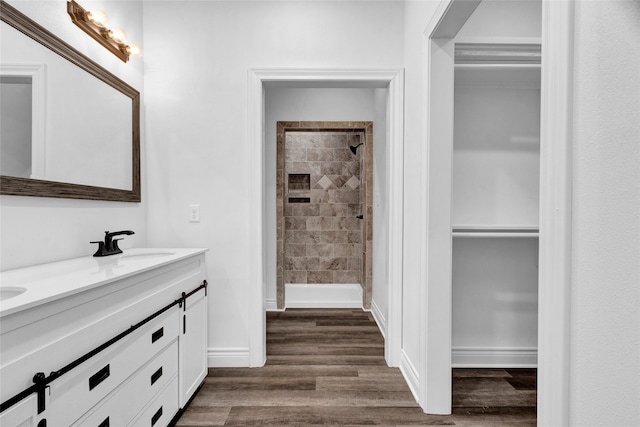 bathroom featuring a tile shower, double vanity, and hardwood / wood-style flooring