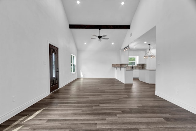 unfurnished living room featuring ceiling fan with notable chandelier, hardwood / wood-style floors, high vaulted ceiling, beamed ceiling, and sink