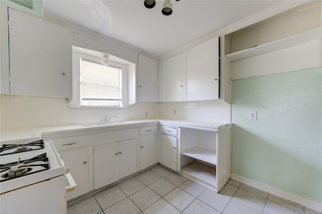 kitchen featuring decorative backsplash, white cabinets, light tile patterned floors, and white gas range oven