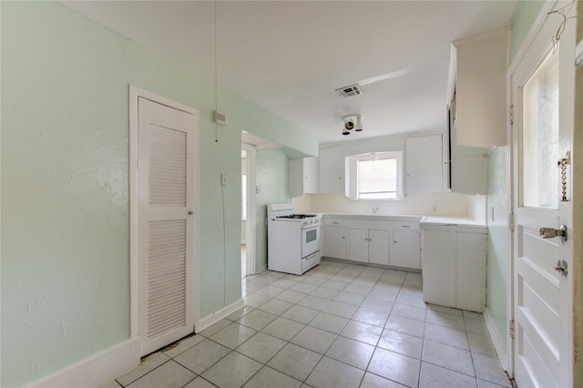 kitchen featuring gas range gas stove, light tile patterned floors, sink, and white cabinetry