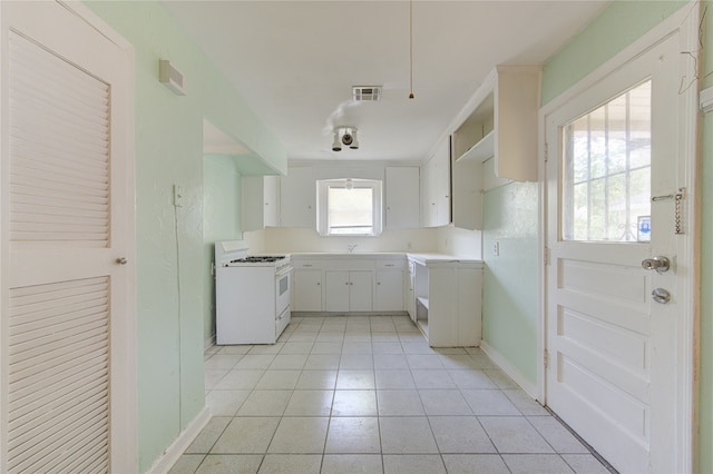 kitchen with gas range gas stove, light tile patterned flooring, and white cabinets