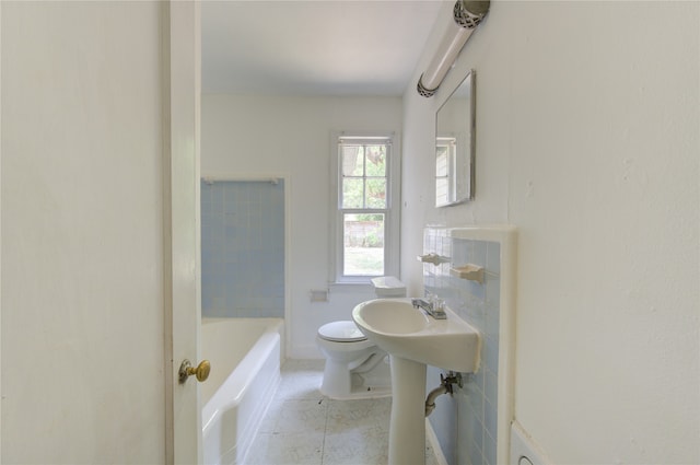 bathroom with tile patterned floors, tiled shower / bath combo, toilet, and tile walls