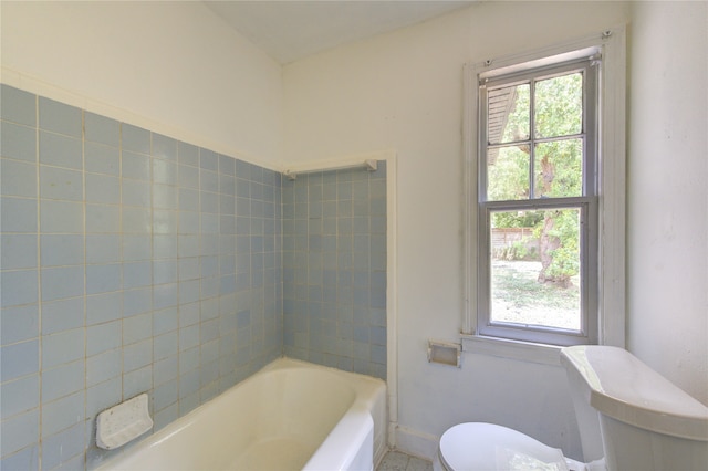 bathroom featuring toilet, tiled shower / bath combo, and a healthy amount of sunlight