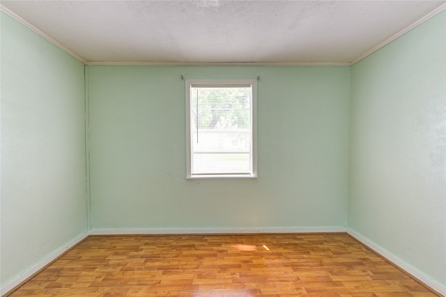 spare room featuring a textured ceiling, light wood-type flooring, and crown molding