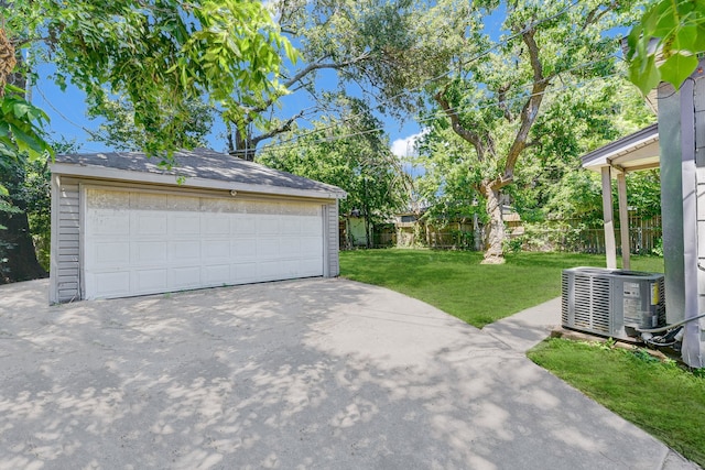 garage with a lawn and central AC unit