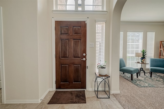 carpeted foyer featuring crown molding