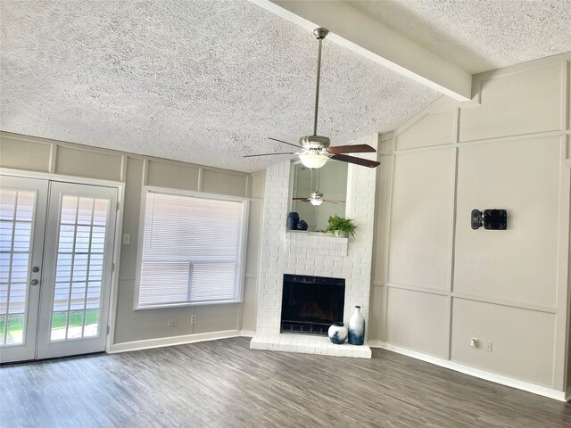 unfurnished living room featuring ceiling fan, a brick fireplace, brick wall, vaulted ceiling with beams, and wood-type flooring