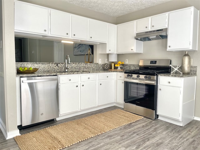 kitchen featuring light hardwood / wood-style flooring, a textured ceiling, appliances with stainless steel finishes, white cabinets, and sink