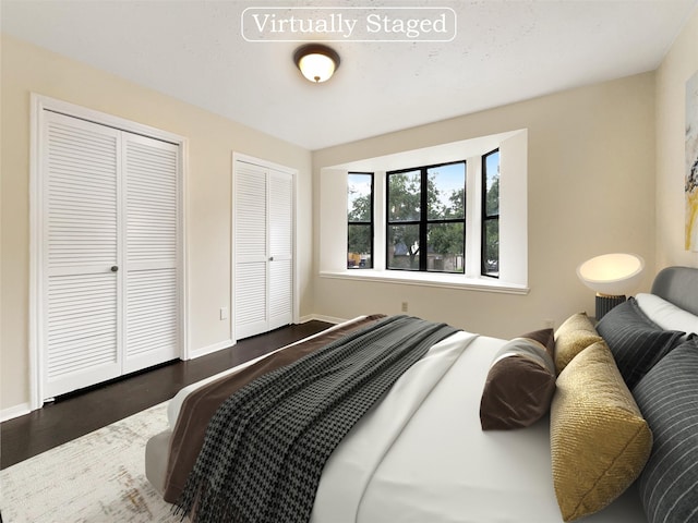 bedroom with dark hardwood / wood-style flooring and multiple closets