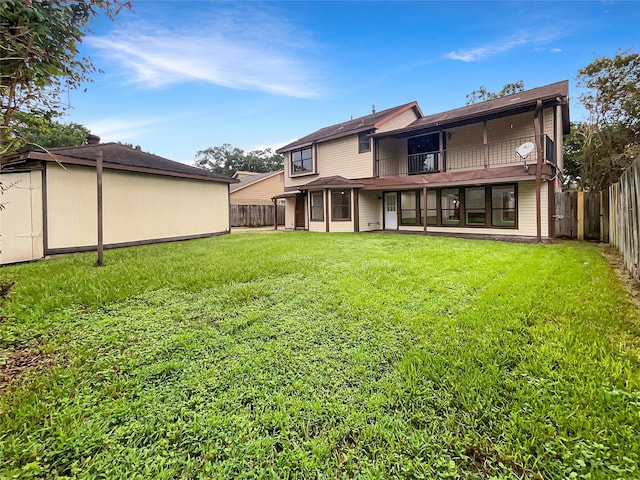 rear view of house with a balcony and a yard