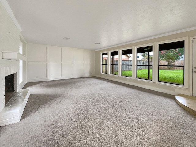 unfurnished living room featuring crown molding, plenty of natural light, carpet floors, and a fireplace