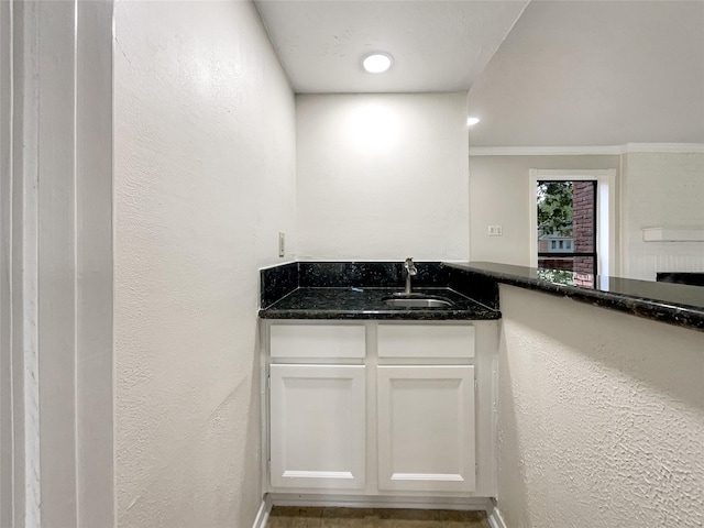 kitchen featuring white cabinetry, dark stone counters, and sink