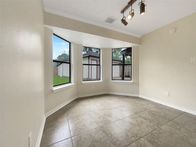 unfurnished room with tile patterned floors, ornamental molding, and a wealth of natural light