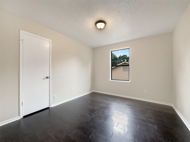 empty room with dark wood-type flooring and a textured ceiling