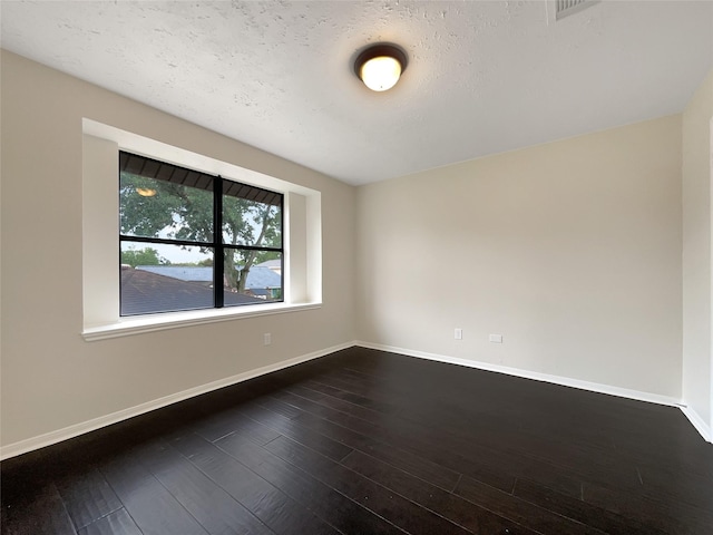 spare room featuring dark hardwood / wood-style floors and a textured ceiling