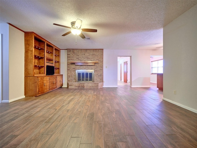 unfurnished living room with hardwood / wood-style flooring, a brick fireplace, a textured ceiling, and ceiling fan