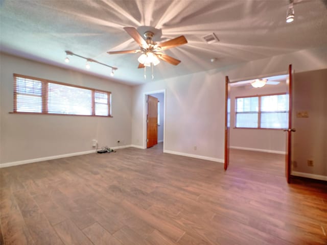 empty room with ceiling fan, wood-type flooring, a textured ceiling, and a wealth of natural light