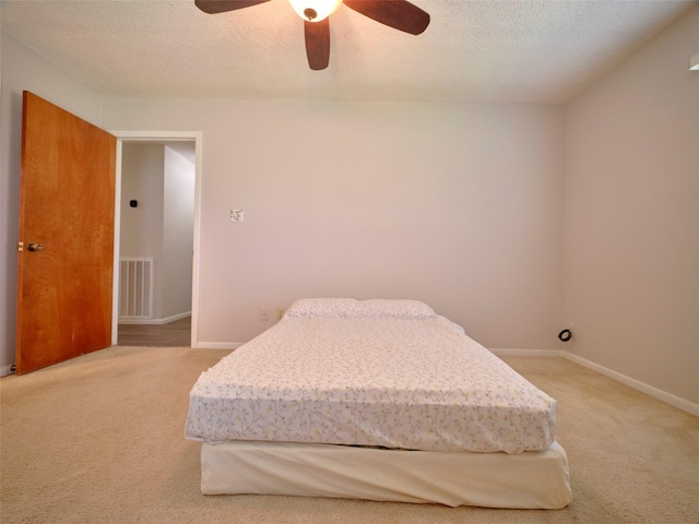 carpeted bedroom featuring ceiling fan and a textured ceiling