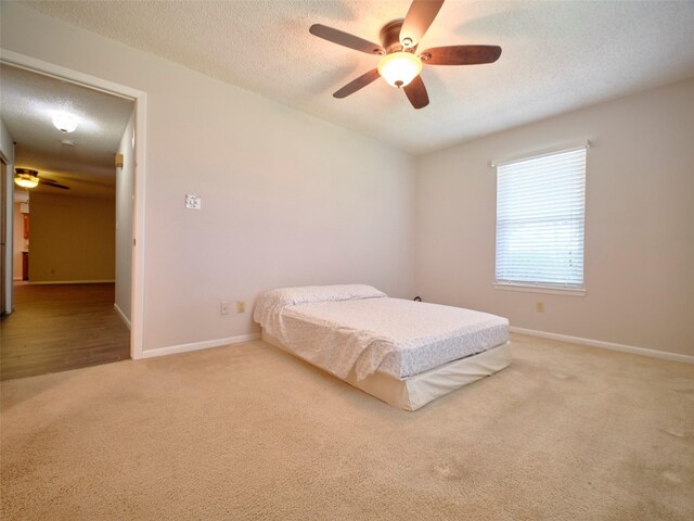 carpeted bedroom with ceiling fan and a textured ceiling