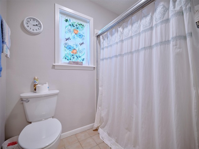 bathroom with a shower with shower curtain, tile patterned floors, and toilet