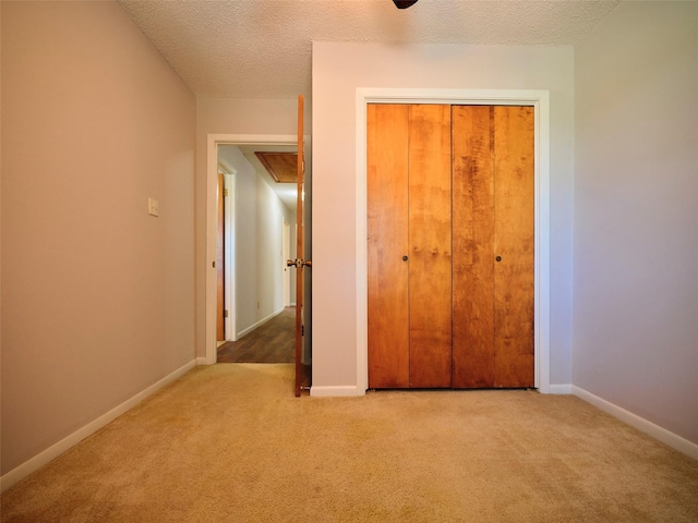 unfurnished bedroom with carpet floors, a closet, and a textured ceiling