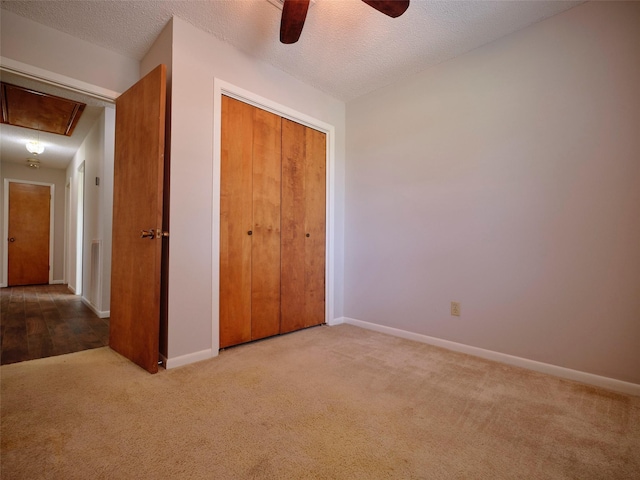 unfurnished bedroom featuring ceiling fan, a closet, light carpet, and a textured ceiling