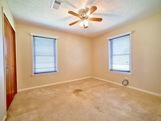 carpeted spare room with ceiling fan and a textured ceiling