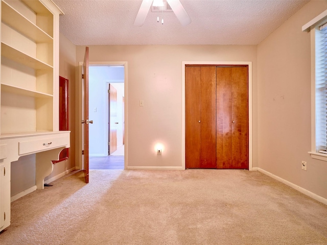 unfurnished bedroom with ceiling fan, light carpet, a textured ceiling, and a closet