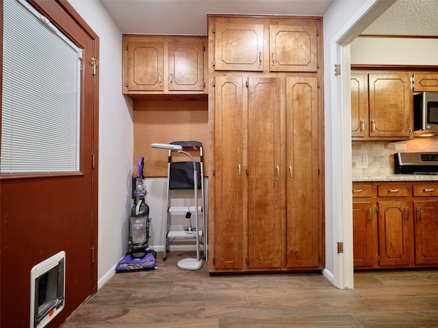 interior space with appliances with stainless steel finishes, heating unit, decorative backsplash, and light hardwood / wood-style flooring