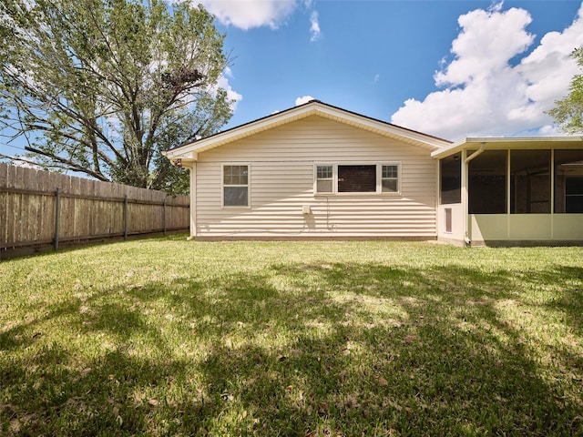 back of house featuring a sunroom and a lawn