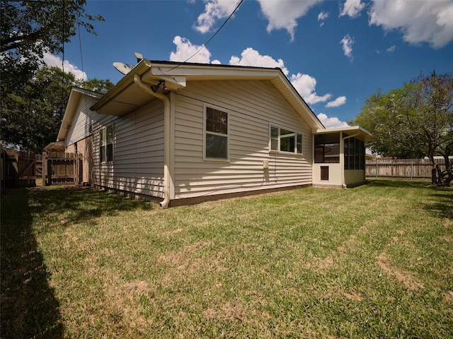 rear view of property with a sunroom and a lawn