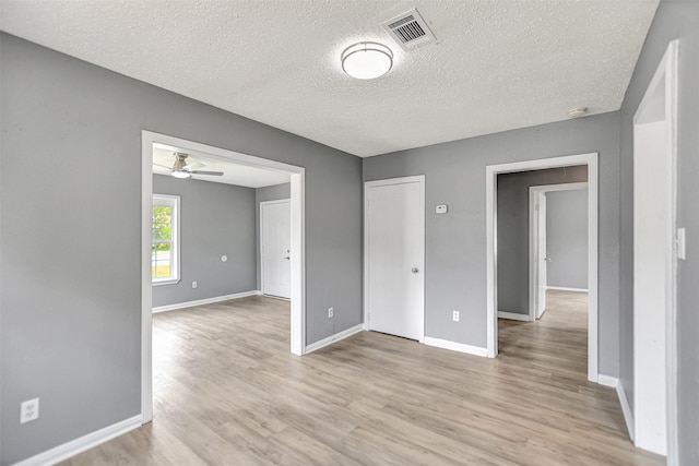 empty room featuring light wood-type flooring, a textured ceiling, and ceiling fan