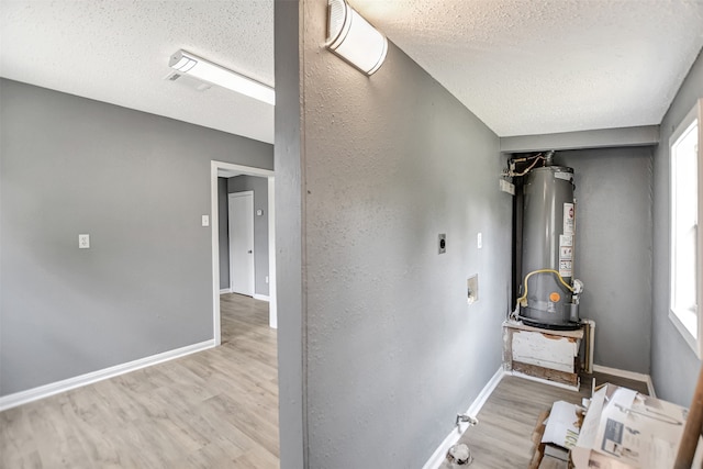 hall featuring gas water heater, hardwood / wood-style flooring, and a textured ceiling