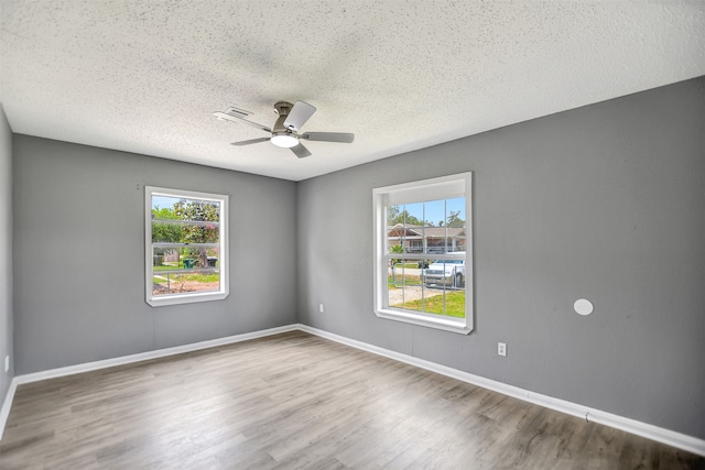 spare room with ceiling fan, hardwood / wood-style flooring, a textured ceiling, and a healthy amount of sunlight