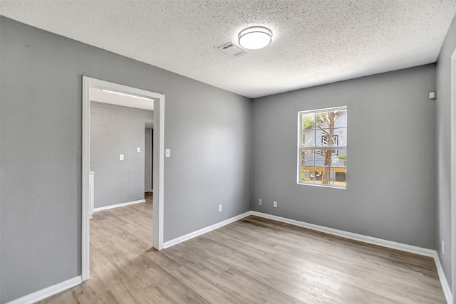 spare room featuring wood-type flooring and a textured ceiling