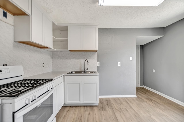 kitchen with light wood-type flooring, sink, white range with gas cooktop, and a textured ceiling